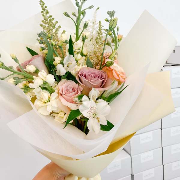 Bouquet of pink roses and white flowers wrapped in cream paper