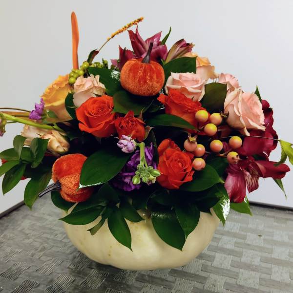 Autumn floral arrangement with roses and lilies in a cream bowl