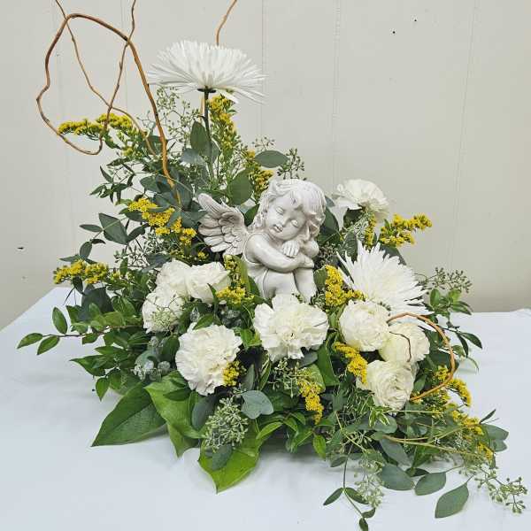 White flowers arranged around a small angel figurine with curly branches