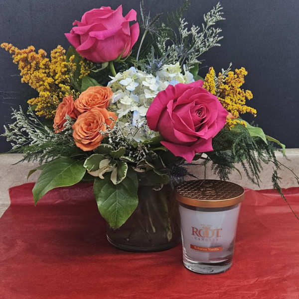 Pink and orange roses in a black vase with a candle beside it