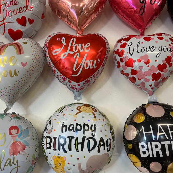 Heart-shaped and round foil balloons with love and birthday messages.