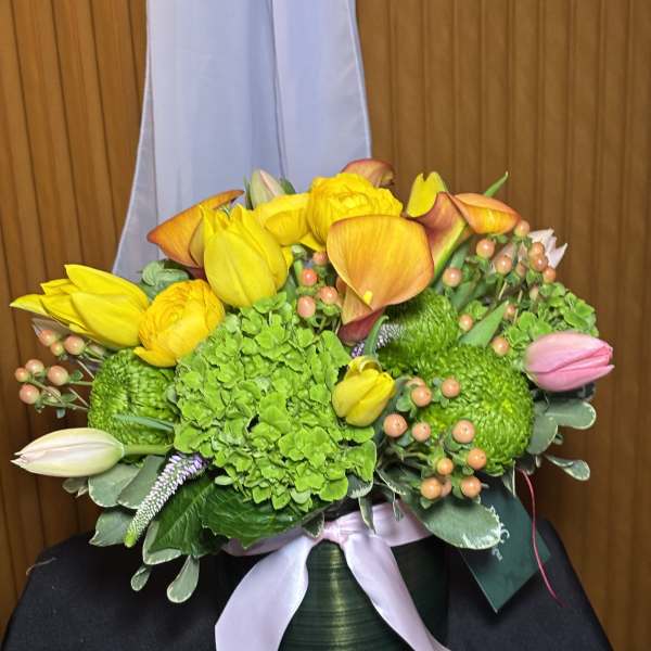 Bouquet of yellow tulips, green hydrangea, and orange calla lilies in a vase
