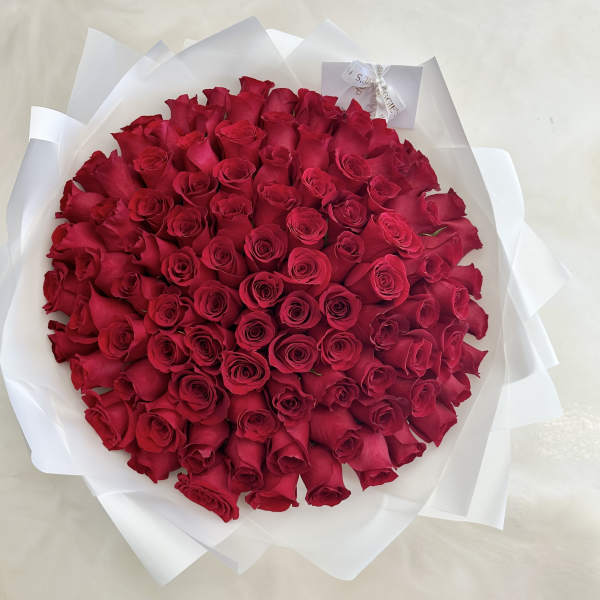 Round bouquet of red roses wrapped in white paper