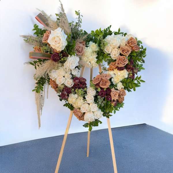 Heart-shaped floral arrangement on an easel with roses and greenery
