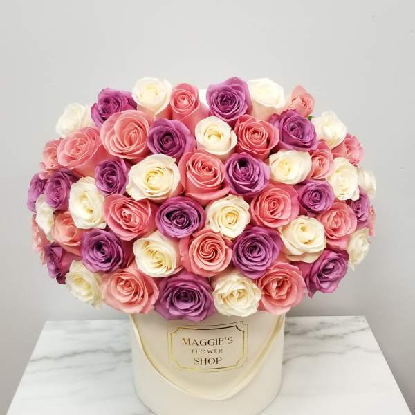 Round bouquet of pink, purple, and white roses in a cream hat box