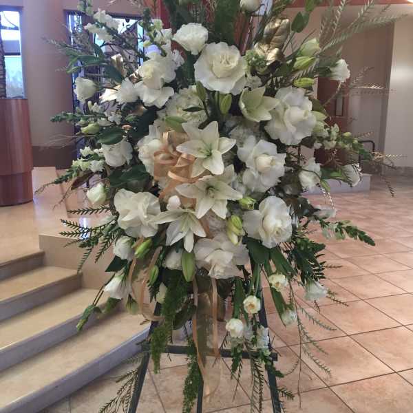 Tall white floral standing arrangement on an easel with ribbon