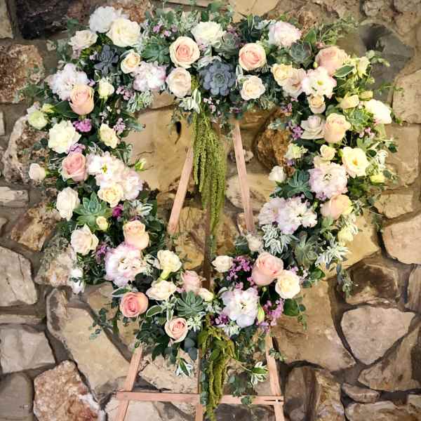 Heart-shaped floral wreath on a wooden easel with pink and white roses
