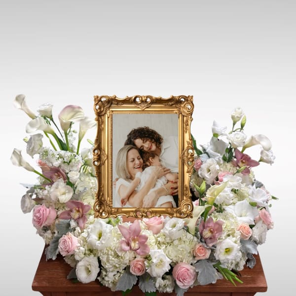 White and pink floral arrangement around a gold picture frame