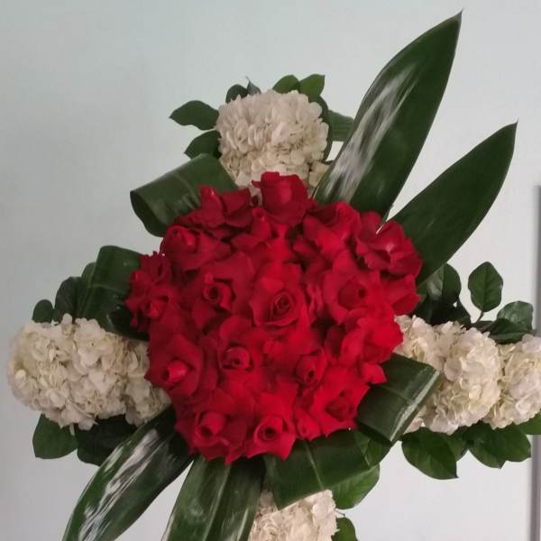 Cross-shaped floral tribute with red roses and white hydrangeas