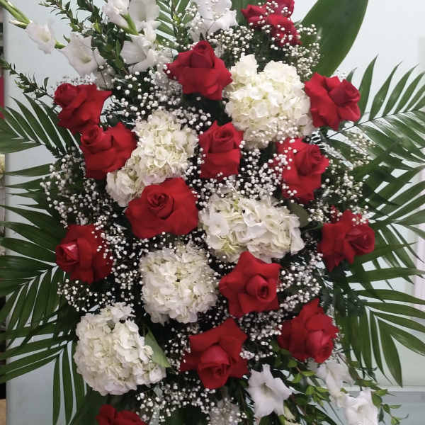 Standing floral spray with red roses and white blooms on a wooden easel