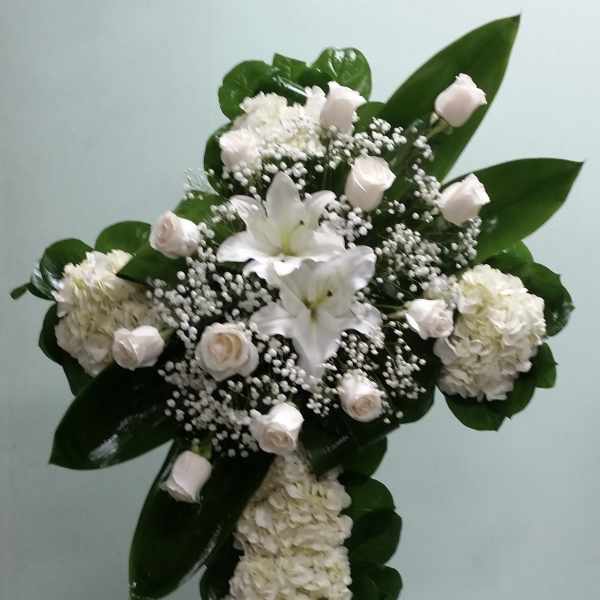 White floral standing spray with lilies, roses, and hydrangeas on an easel