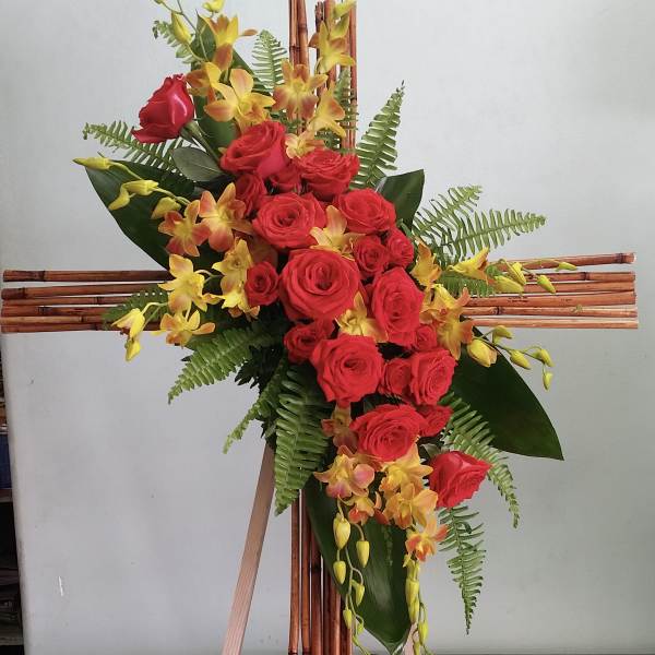 Tall floral arrangement of red roses and yellow orchids on a wooden easel