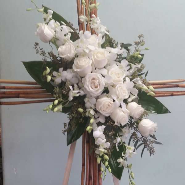 White floral spray on a bamboo stand with pink ribbons