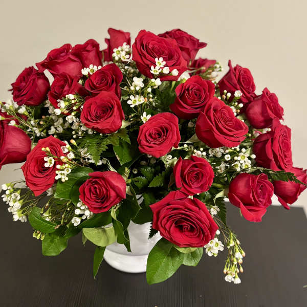 Bouquet of red roses with small white filler flowers in a white vase