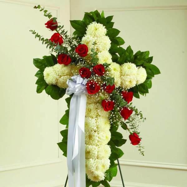 Cross-shaped floral spray with red roses and white chrysanthemums on a stand