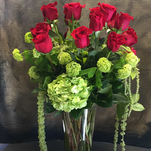 Red roses and green hydrangea in a tall glass vase