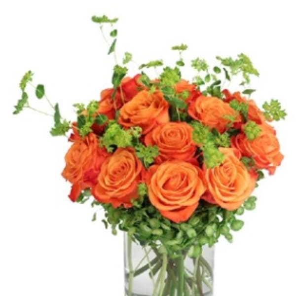 Orange roses in a clear glass vase with green filler