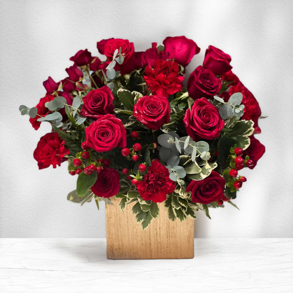 Red roses and carnations in a wooden box with eucalyptus