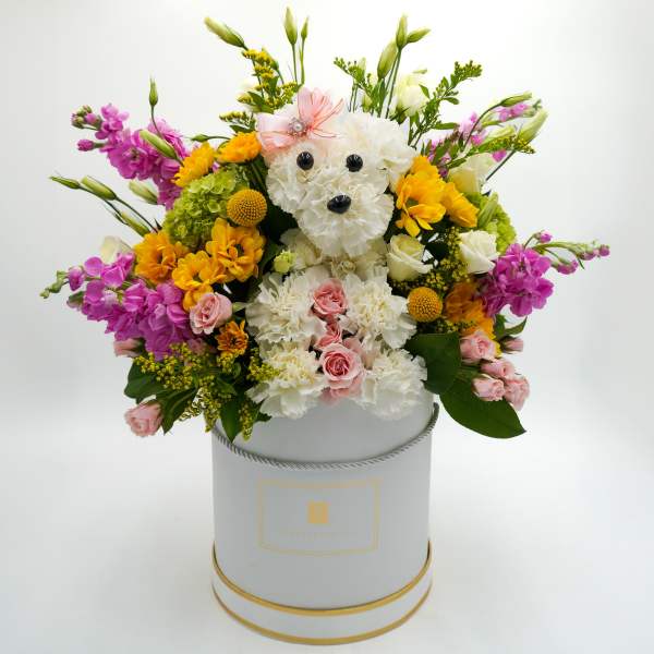 Flower arrangement in a hatbox with a teddy bear face made of white blooms