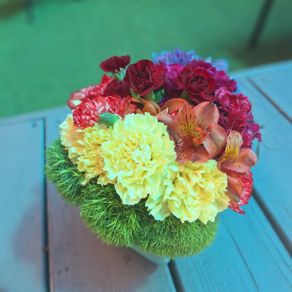 Colorful bouquet with carnations and alstroemeria in a green textured base