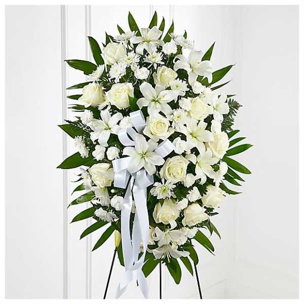 White floral standing spray with roses and lilies on an easel