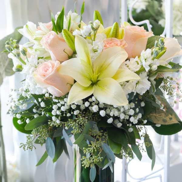 Bouquet of pale roses and lilies in a tall glass vase