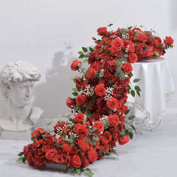 Large cascading arrangement of red roses with greenery on a white pedestal
