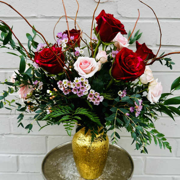 Bouquet of red and pale pink roses in a gold vase