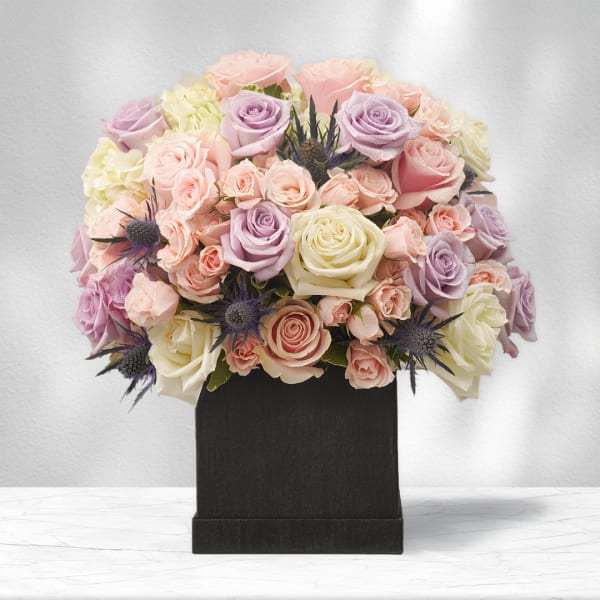 Pastel roses and hydrangeas arranged in a black box
