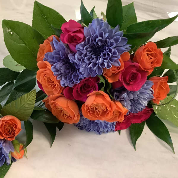 Bouquet of orange and pink roses with purple flowers and glossy leaves