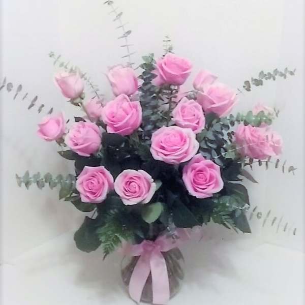 Pink roses arranged in a clear vase with eucalyptus foliage
