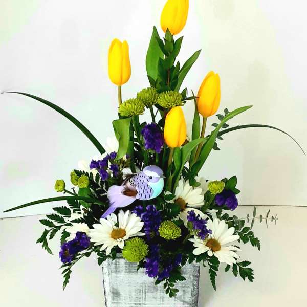 Yellow tulips with white daisies and purple filler in a silver container