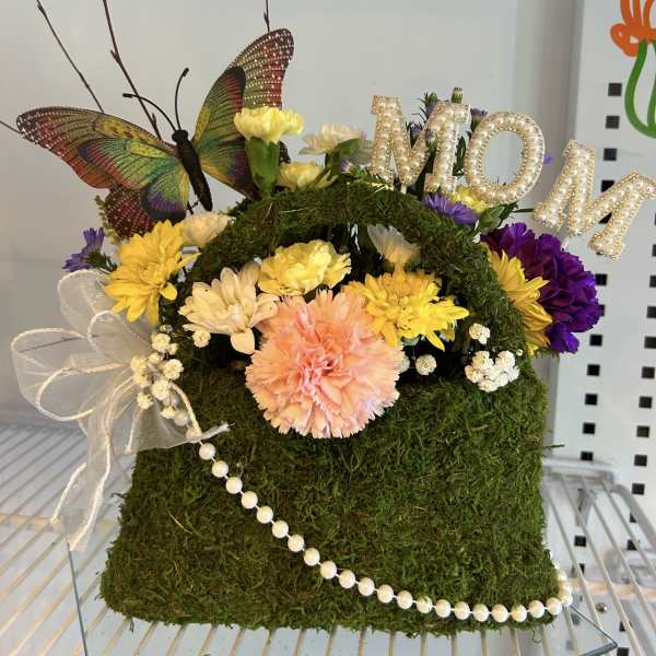 Moss-covered floral handbag with mixed flowers, butterfly, and pearl trim
