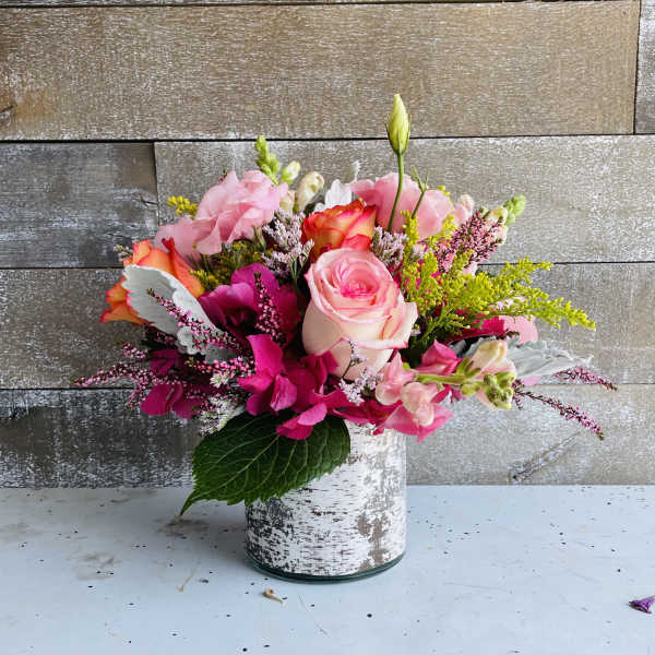 Pink and orange mixed flower arrangement in a white vase