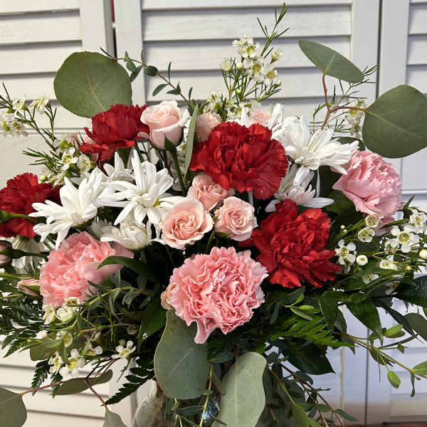 Bouquet of red and pink carnations with white daisies in a glass vase