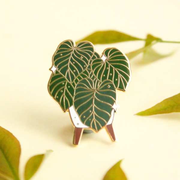 Green leaf-shaped enamel pin on a small stand