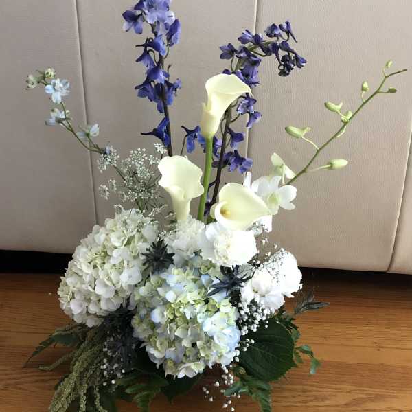 White hydrangeas with blue delphinium and white calla lilies in a low arrangement