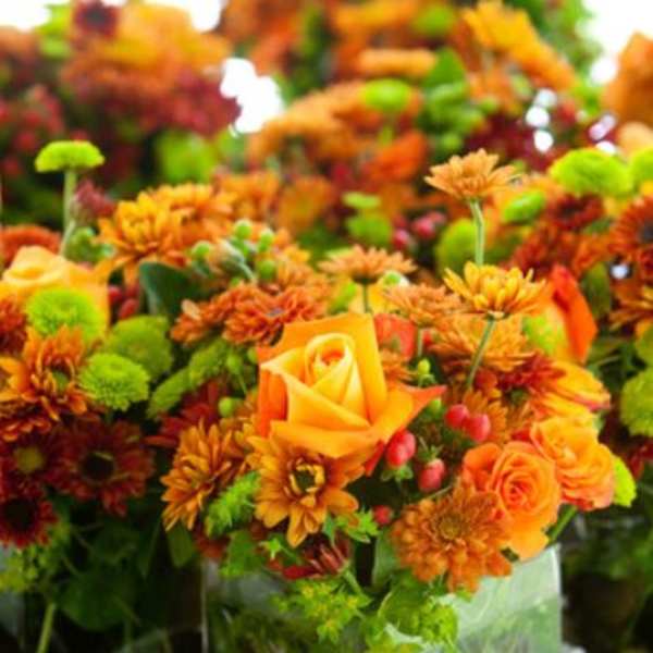 Orange and green floral arrangement in a clear glass vase
