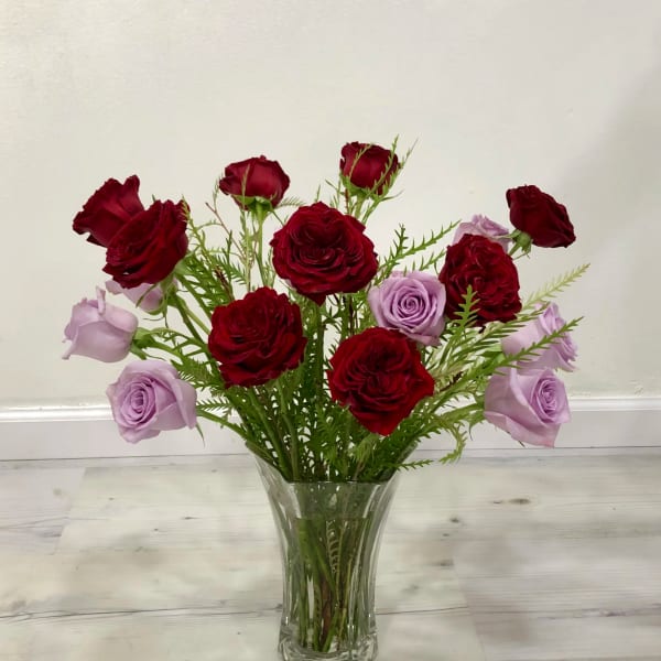 Red and lavender roses arranged in a clear glass vase