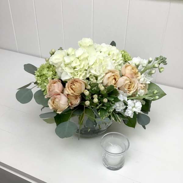 Peach roses and white hydrangeas in a glass bowl vase