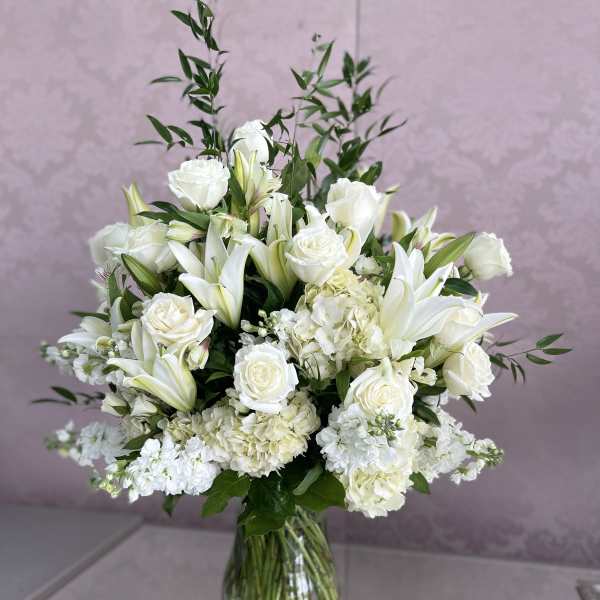 White roses and lilies arranged in a clear glass vase