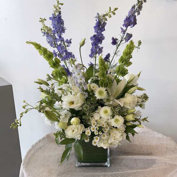 White and purple floral arrangement in a square glass vase