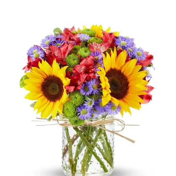 Bouquet of sunflowers, purple daisies, and red flowers in a glass vase