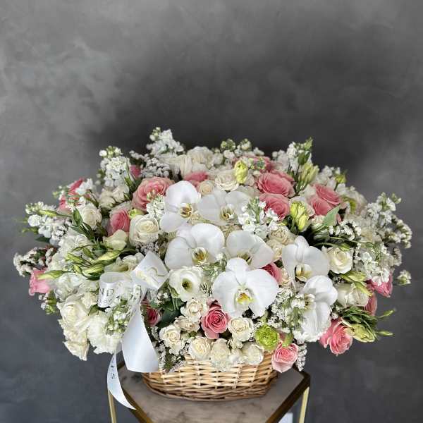 Large basket arrangement of white orchids, pink roses, and white spray flowers