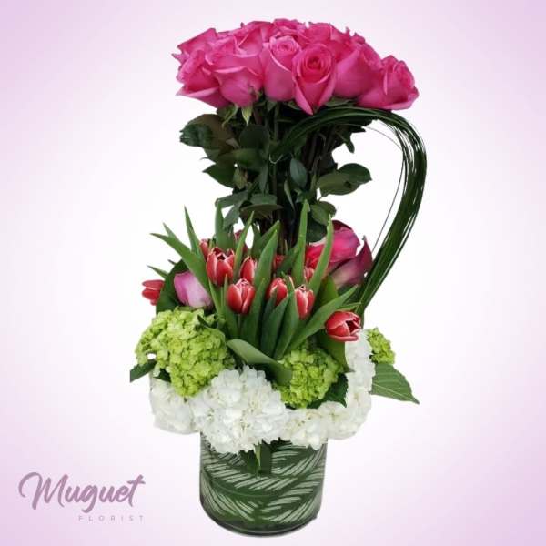 Tall bouquet of pink roses and red tulips in a patterned vase