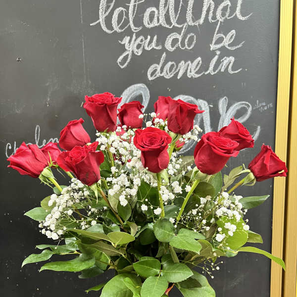 Red roses arranged in a red glass vase with white baby's breath