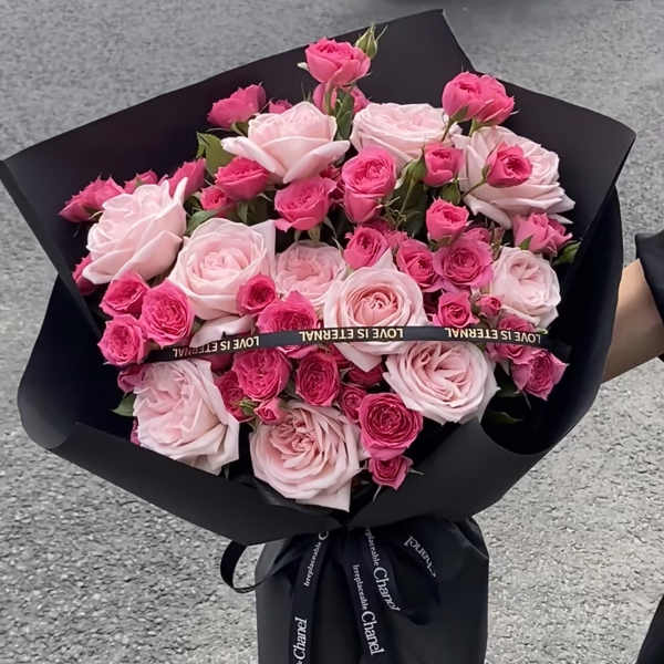 Bouquet of pink roses wrapped in black paper with a ribbon