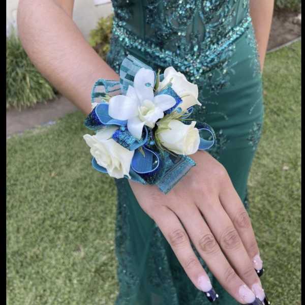 White corsage with blue ribbon on a person's wrist