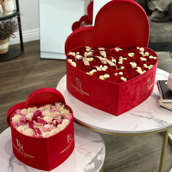 Heart-shaped red boxes filled with roses in pink, white, and red.