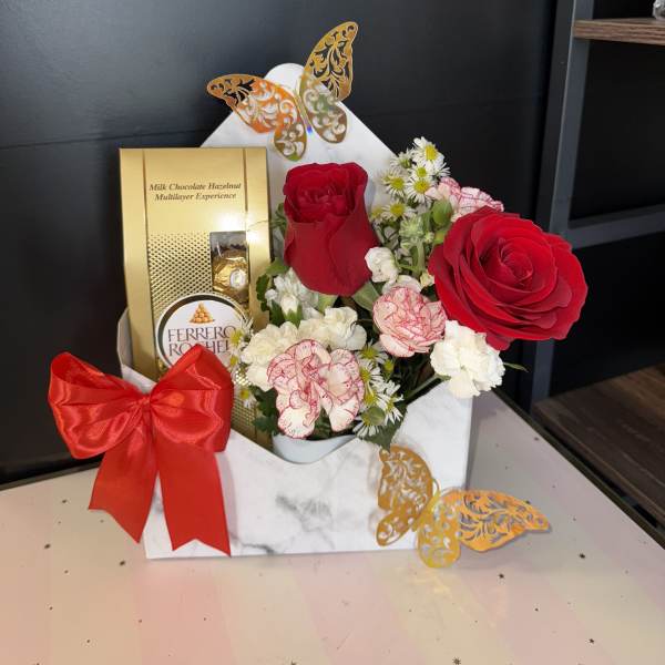Gift box with red roses, carnations, and chocolates tied with a red bow